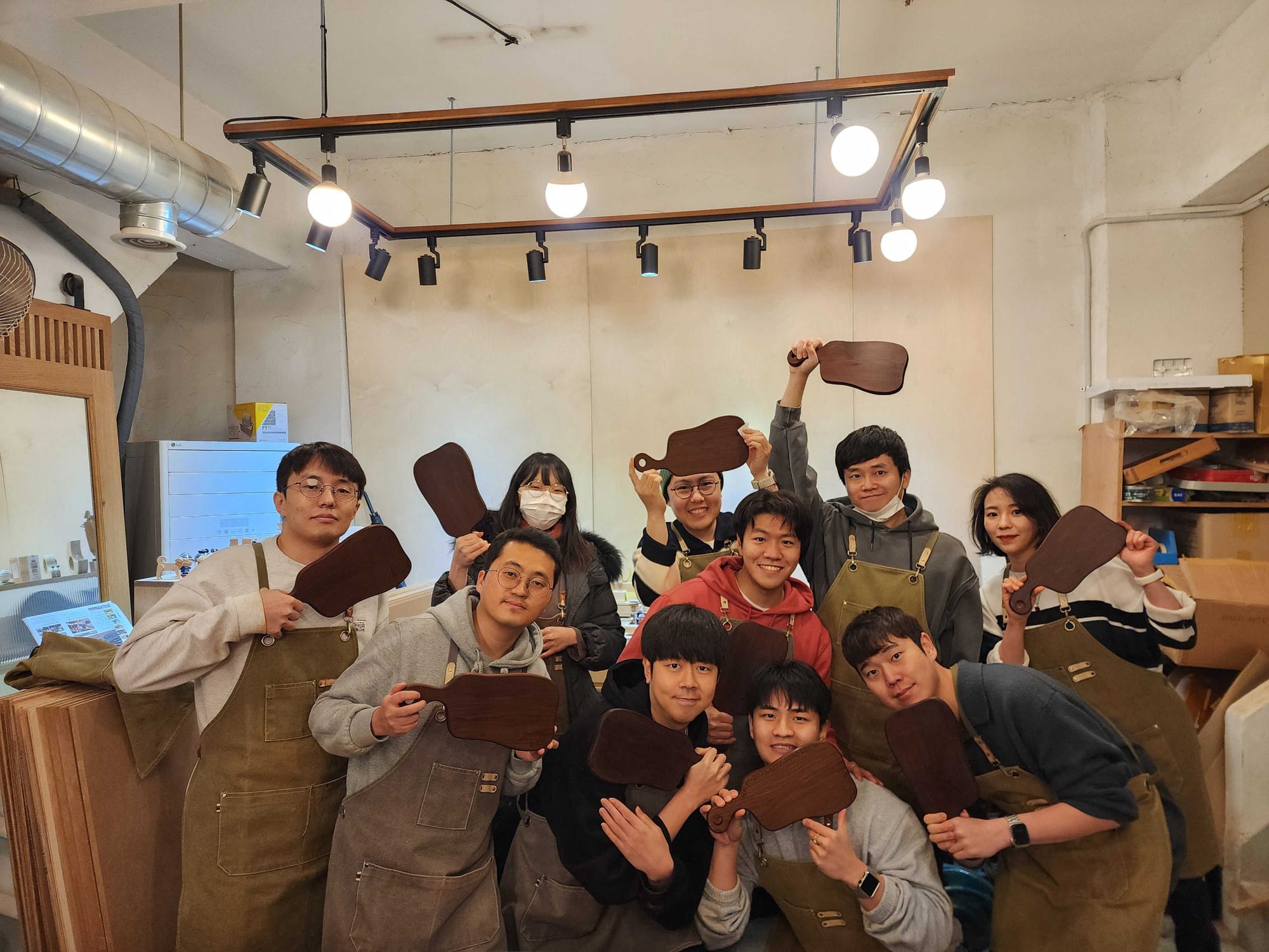 The Seoul team at a woodworking workshop holding cutting boards